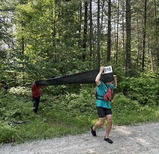 Two canoe paddlers portaging a canoe
