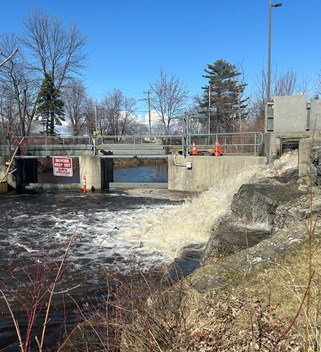 Concrete dam with water being pumped from Parks Creek to Lake Nipissing around the dam